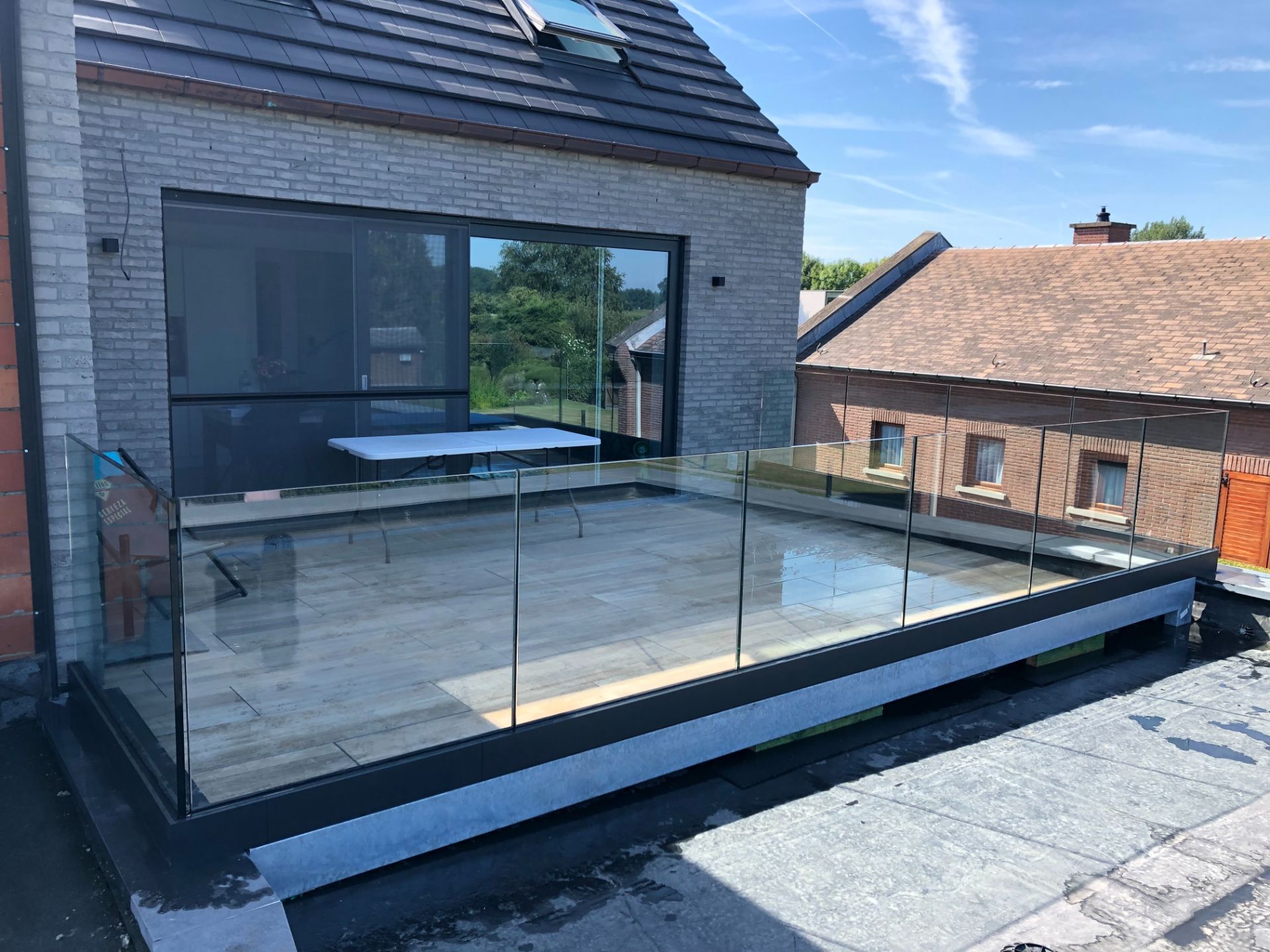 Glazen balustrade rondom een dakterras bij een moderne woning