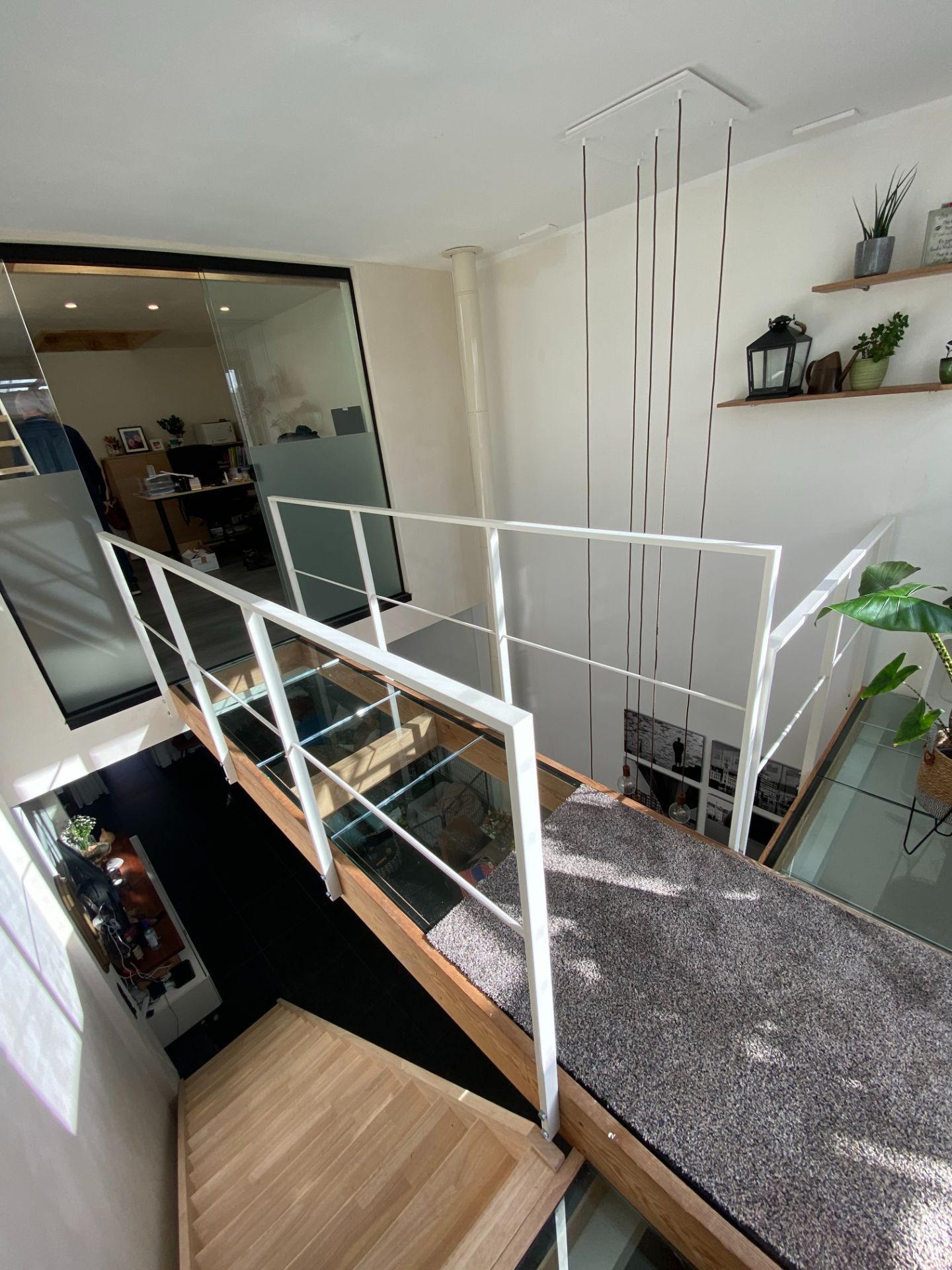 Witte stalen leuning met glas rond een vide in een moderne woning